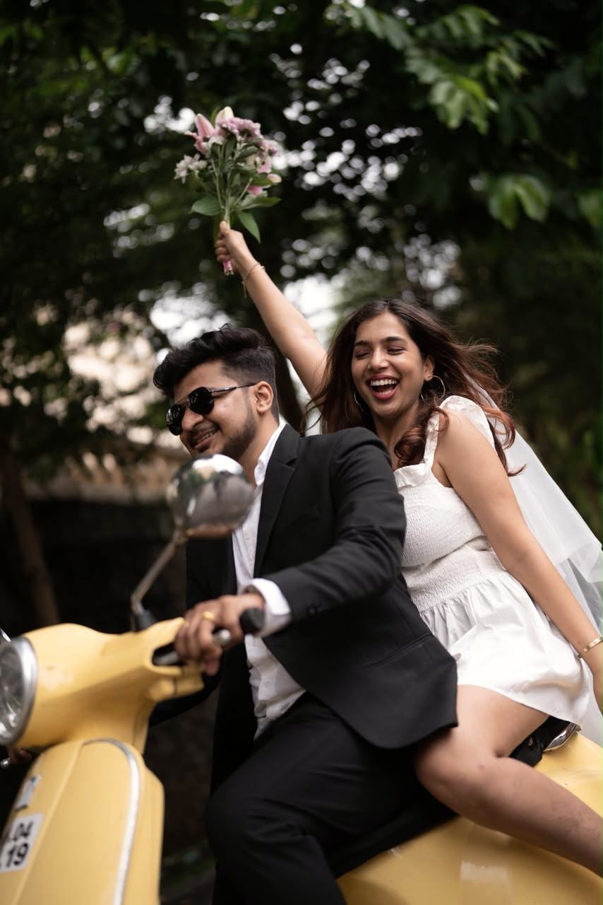 Ravina and Varad laughing together on a yellow scooter